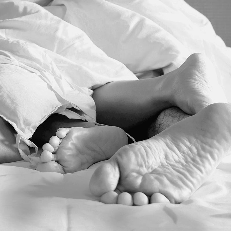 Feet of a couple in bed under blanket